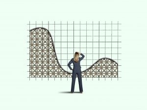 A rear view of a concerned businesswoman as she places her hand on her head and looks up at a rollercoaster that is the stock market. Montagne russe et bourse